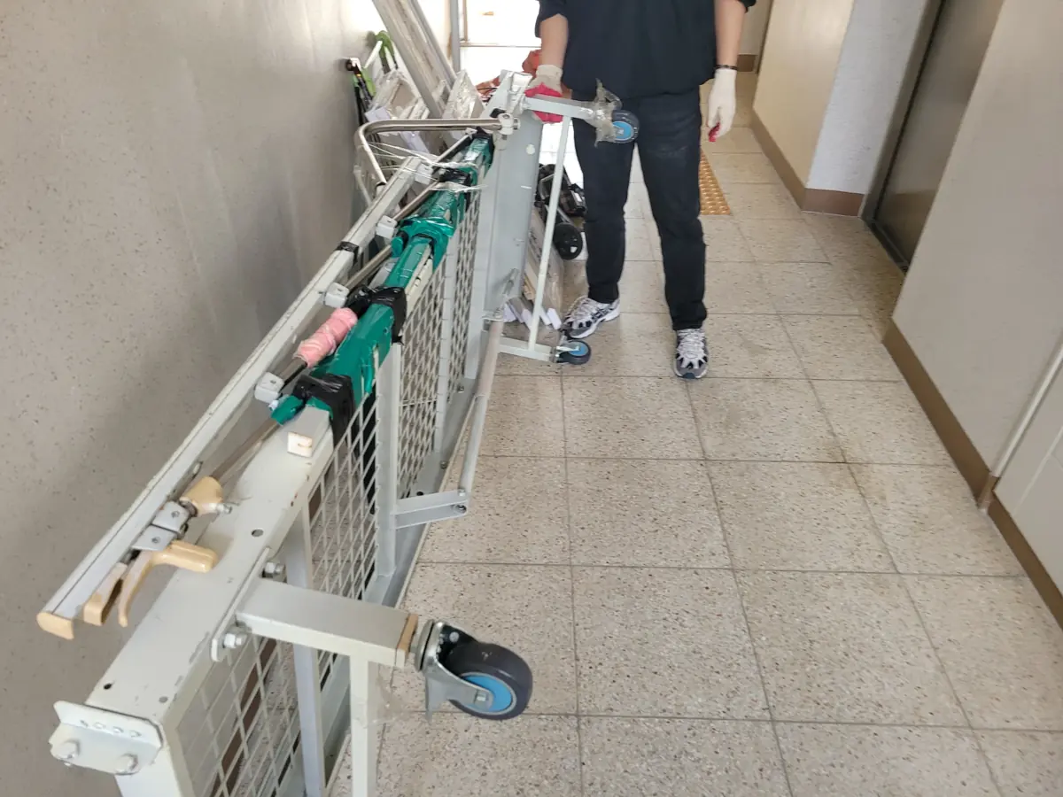 작업자가 복도 난간 옆을 지나 물품을 이동하는 모습