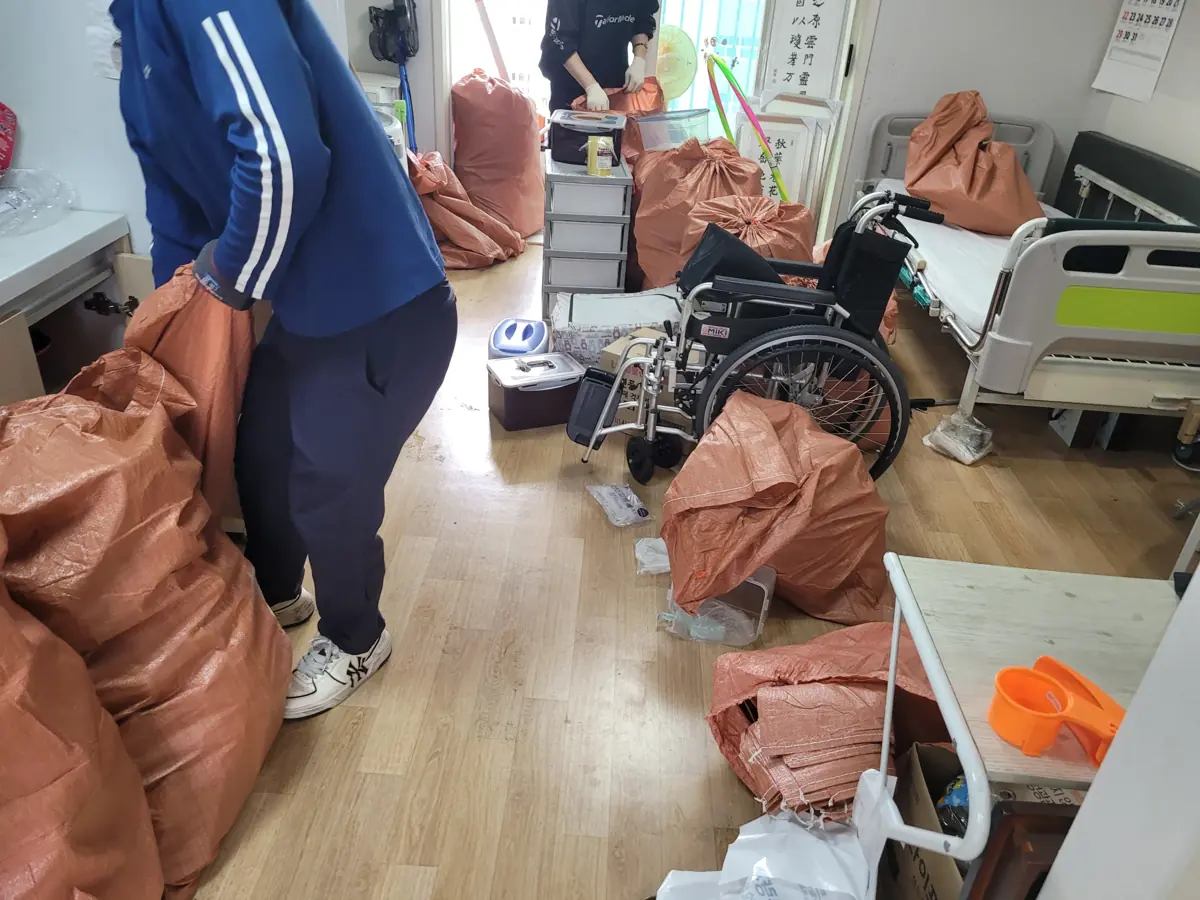 작업자가 방 안 자루와 가구 사이에서 물품을 정리하는 현장