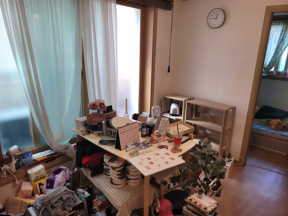 테이블과 선반 위에 생활소품이 쌓인 방