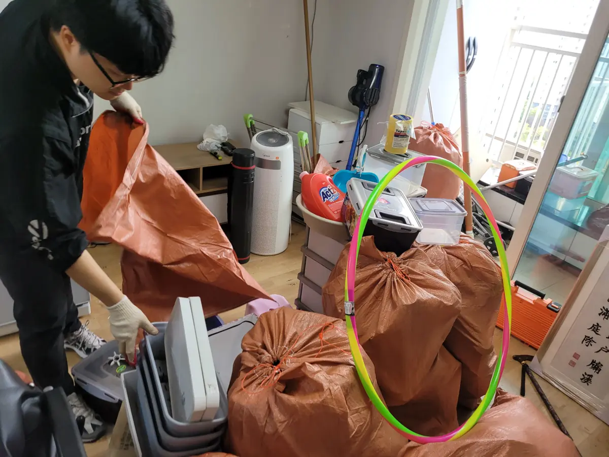 작업자가 방 안에서 자루에 물품을 분류해 담는 집정리 작업